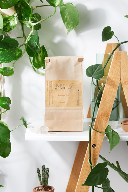 Wooden package labeled 'Butterfly Organics' on a white surface with green plants around.