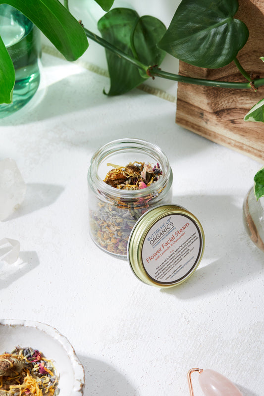 Jar of dried herbs with a label on a white surface with plants in the background