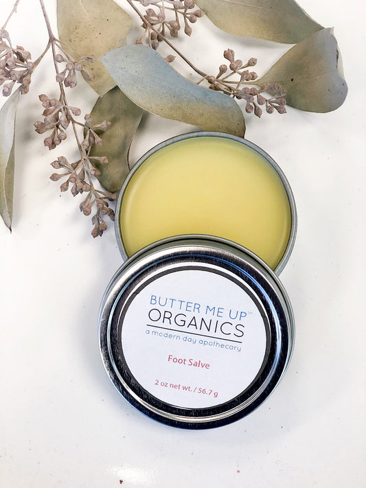 Butter Me Up Organics foot salve tin with eucalyptus leaves on a white background