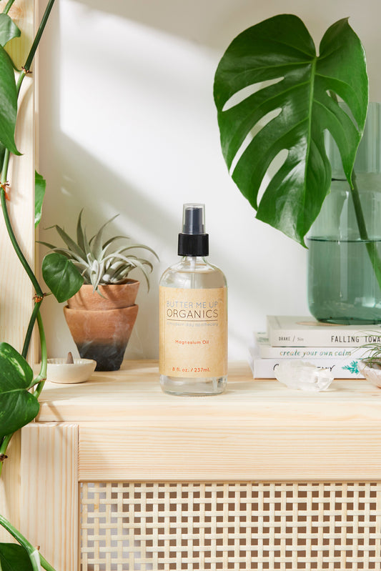 Bottle of 'The Organics' product on a shelf with plants and books in the background