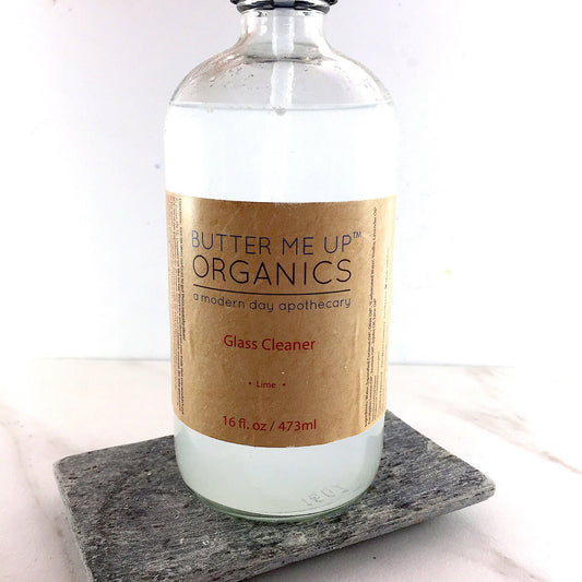 Glass bottle of Butter Me Up Organics Glass Cleaner on a marble surface