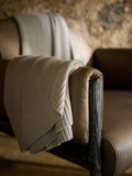 Dove Grey Classic Knit Blanket draped over a leather chair. |Color:Dove Grey