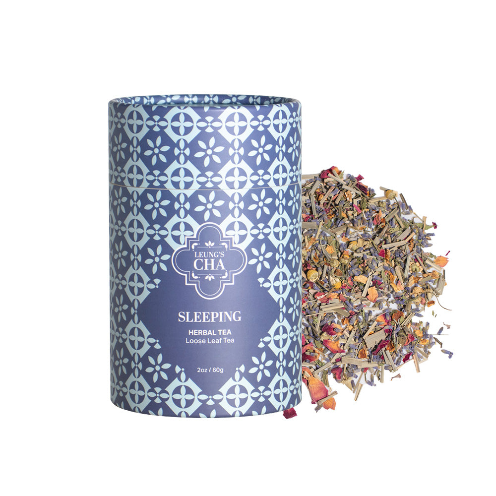 Tea canister with decorative pattern and 'Leininger Cha' branding, accompanied by a scattering of loose tea leaves on a white background.