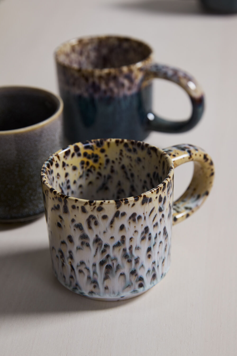 Three ceramic mugs with different patterns on a neutral background