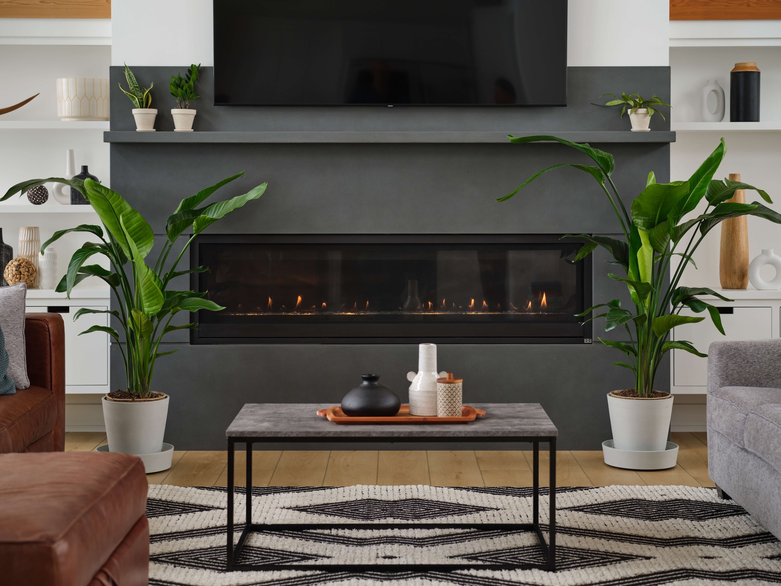Modern living room with a fireplace, plants, and a coffee table.