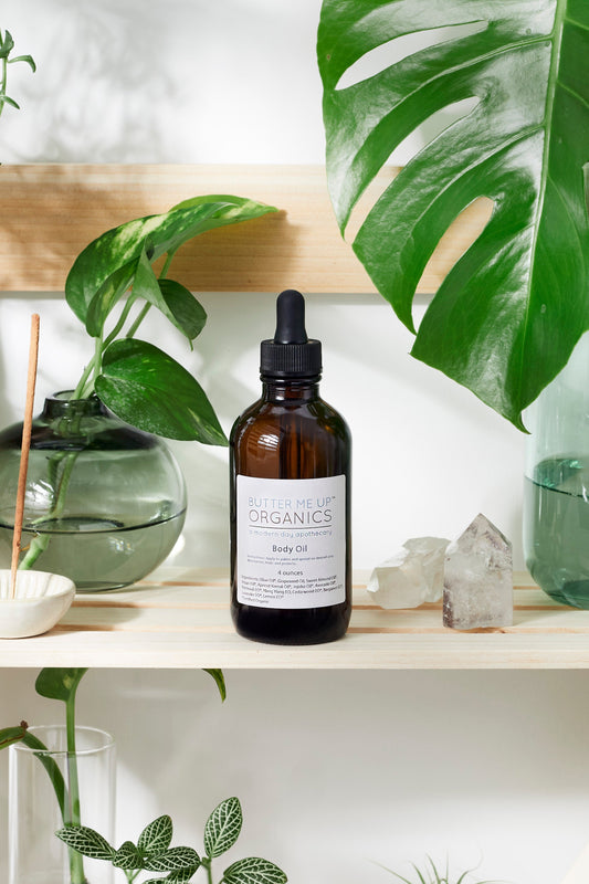 Bottle of body oil on a shelf with plants and crystals in the background