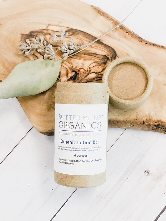 Butter Me Up Organics organic lotion bar on a wooden surface with a white background