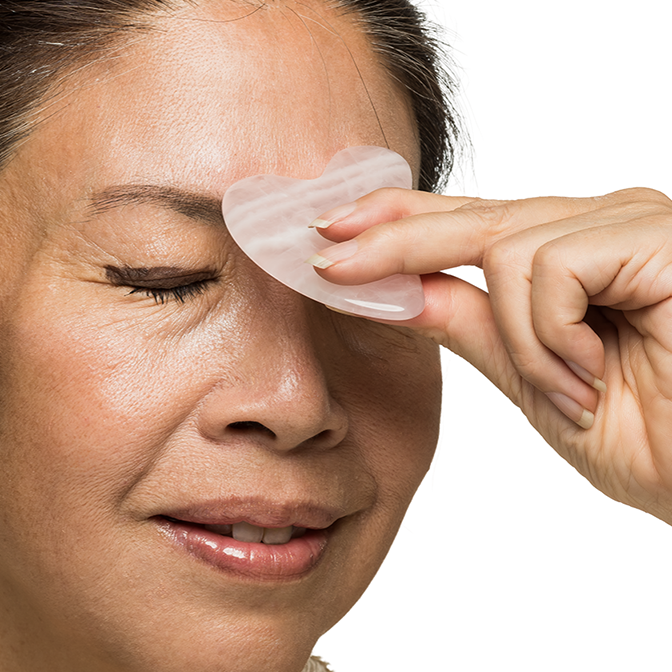 Person using a gua sha tool on their face with a white background