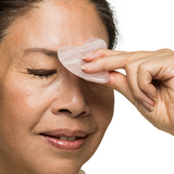 Person using a gua sha tool on their face with a white background