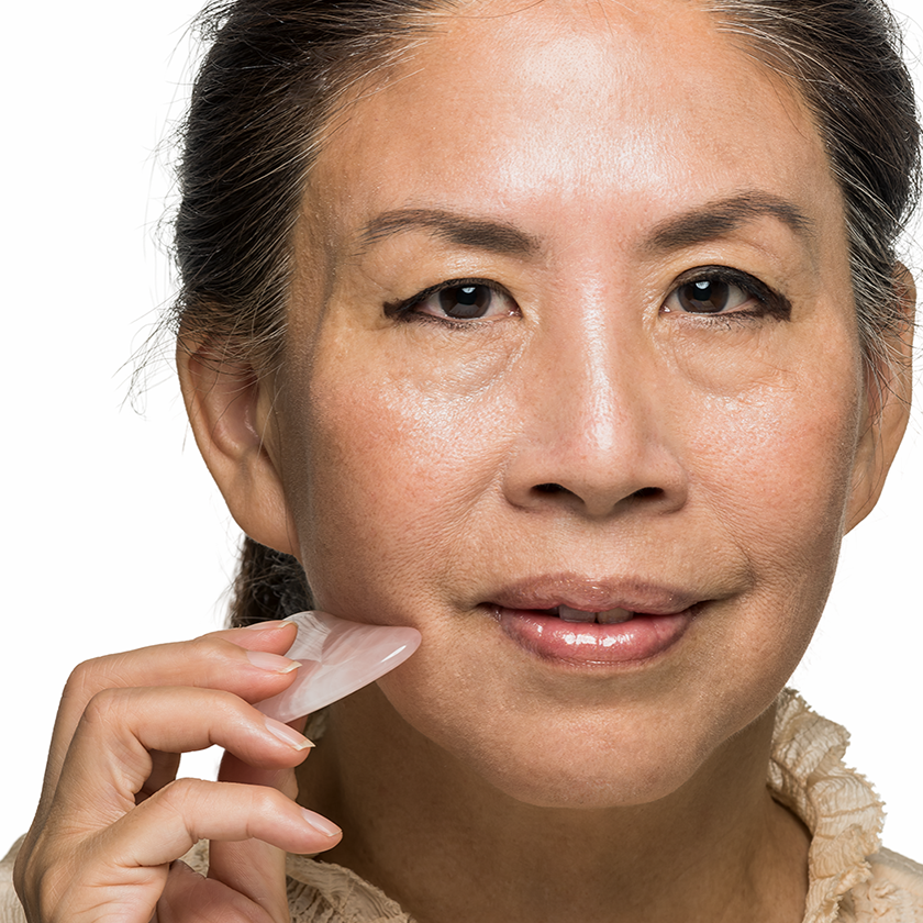 Woman applying a skincare product to her face on a white background