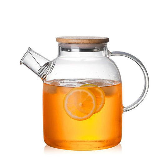 Clear glass teapot with wooden lid filled with iced tea and lemon slices on a white background