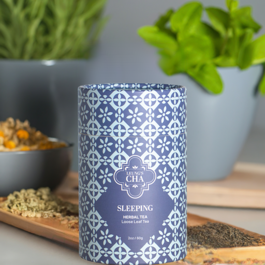 Blue and white patterned tea canister labeled 'Sleeping Herbal Tea' on a wooden surface with plants in the background.