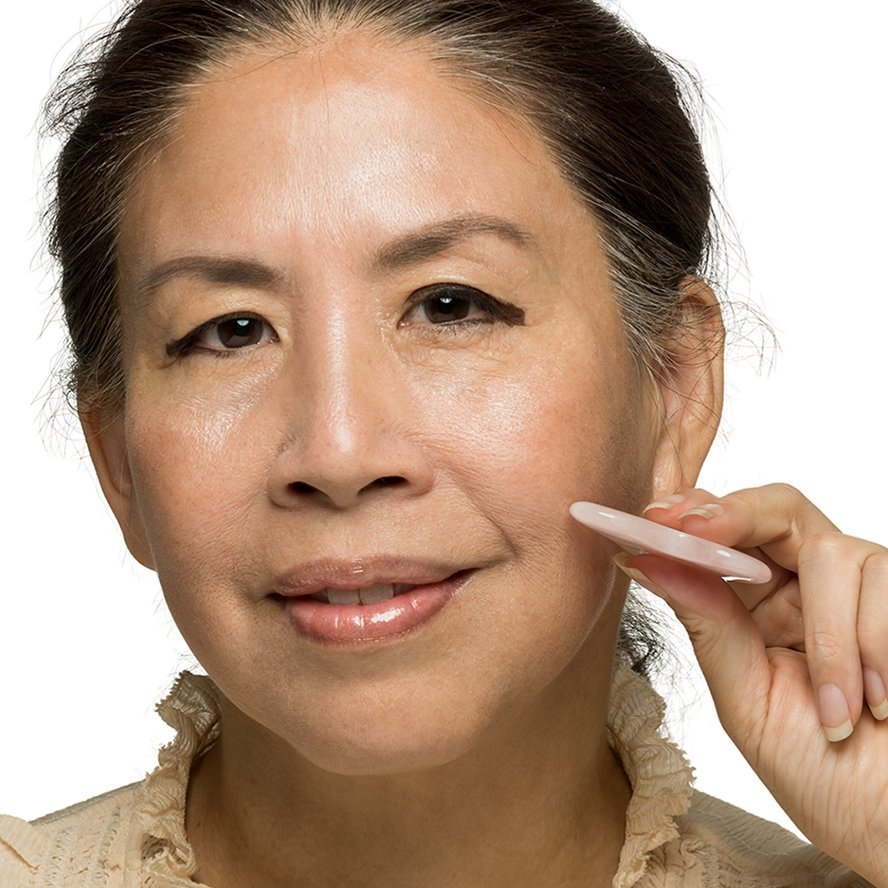 Woman applying cream to her face with a white background