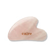 Pink gua sha tool with 'caire' branding on a white background