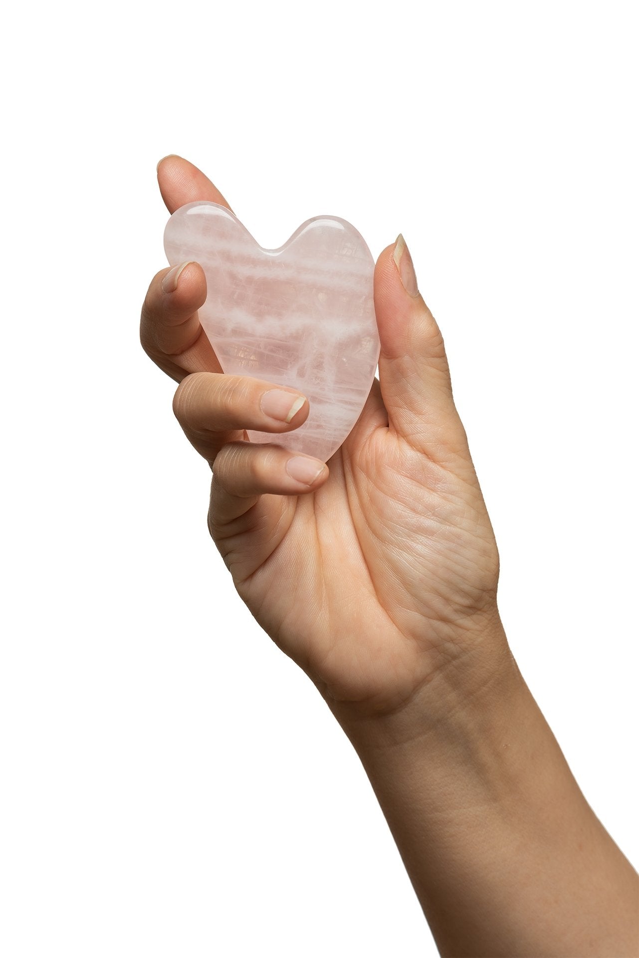 Hand holding a heart-shaped rose quartz crystal on a white background