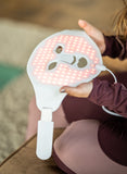 Person holding a white device with pink LED lights on a blurred background