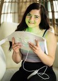 Woman holding a white electronic device with green light on a blurred indoor background