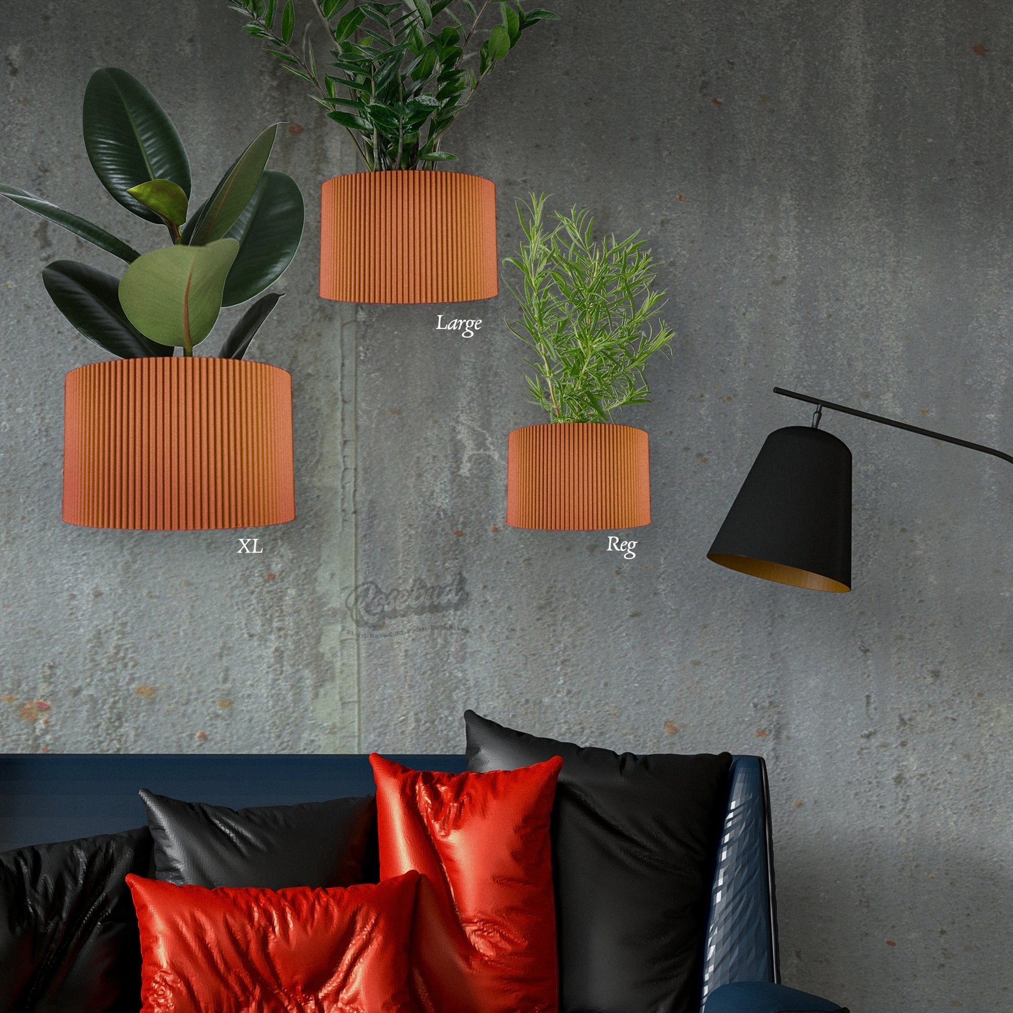 Three orange wall planters of different sizes on a gray wall with a black lamp and red cushions on a sofa.
