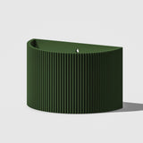 Green ribbed candle on a light gray background