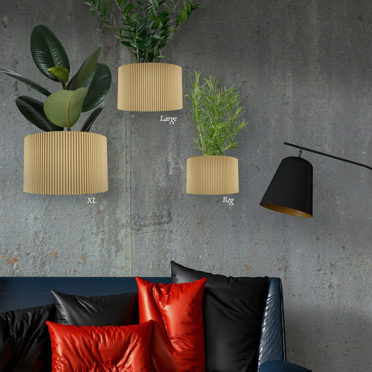 Three decorative planters with plants on a gray wall above a sofa with colorful pillows.