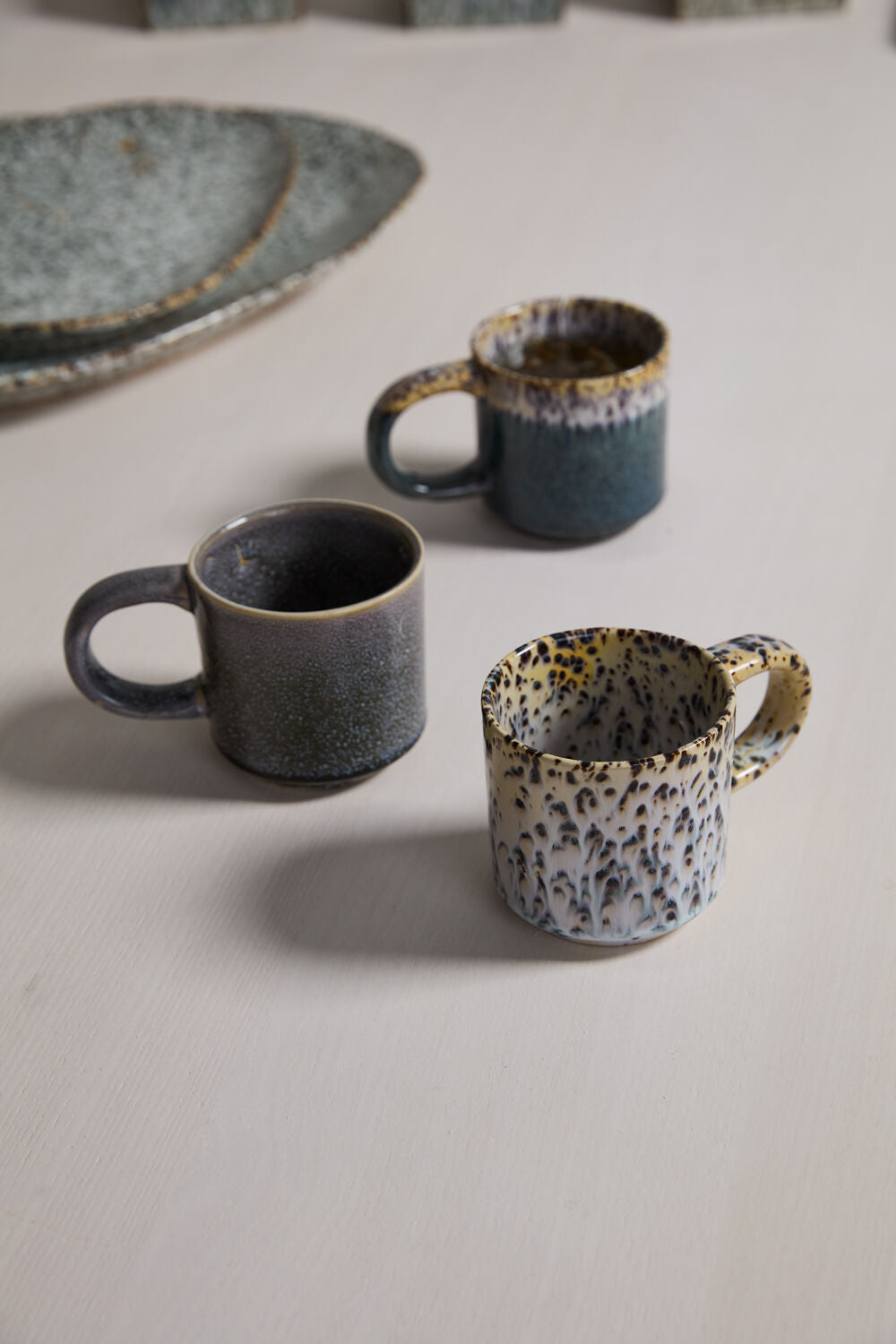 Two ceramic mugs on a textured surface
