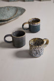 Two ceramic mugs on a textured surface