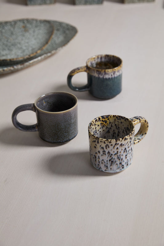 Two ceramic mugs on a textured surface