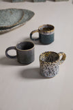 Two ceramic mugs on a textured surface